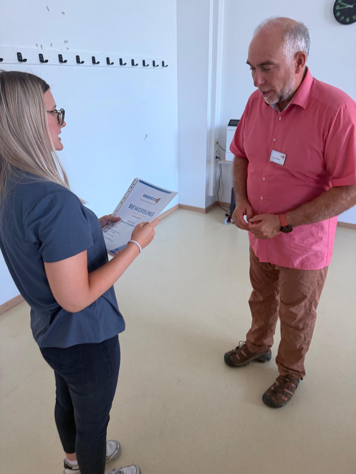Workshop_AK_Bewerbung_7 Schüler:in spricht im Workshop mit einer/m Vortragenden über eine Bewerbungsmappe.