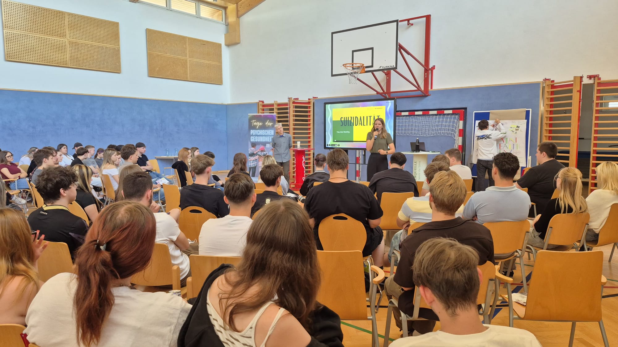 Mental Health Days 1.LG 2026/27 Schülerinnen und Schüler verfolgen in der Turnhalle einen Vortrag zum Thema Suizidalität im Rahmen eines Tages zur psychischen Gesundheit.